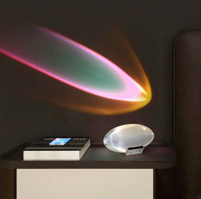 Aurora lamp casting a swirling pink, teal, and gold light beam across a cozy bedroom wall.