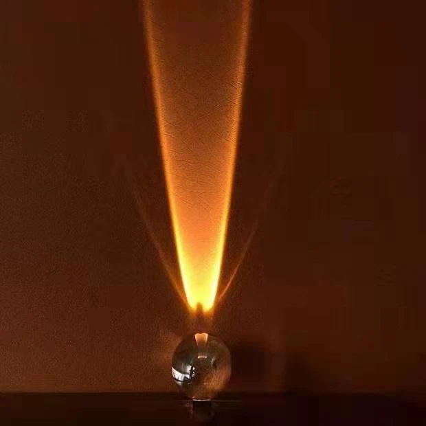 Sunset projection lamp casting a warm amber glow through a crystal orb onto the bedroom wall.