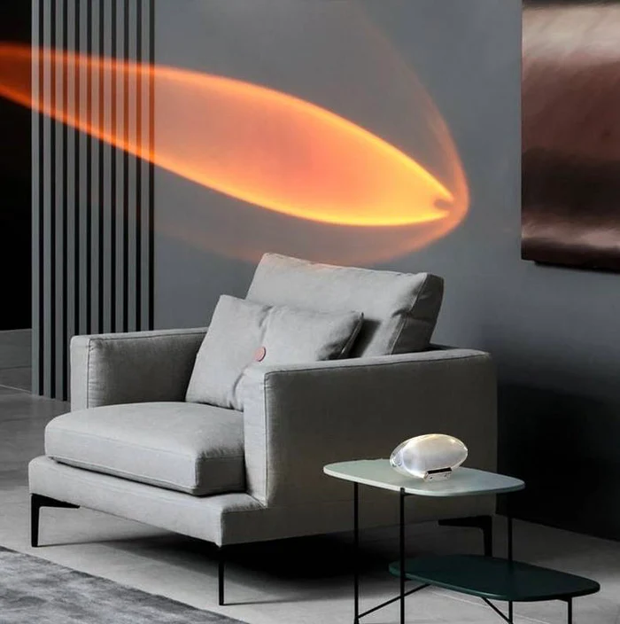 Sunset projector lamp beaming a warm orange glow above a grey armchair in the living room.